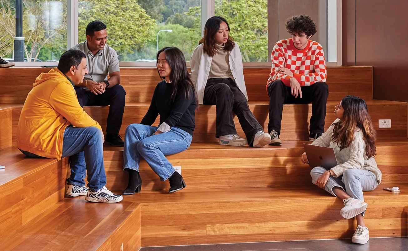 ANU students sitting together on the steps, in conversation.